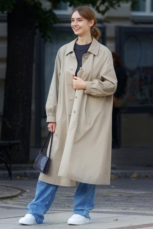 22 - Young woman in an Arket cotton-blend trench coat features a relaxed, oversized silhouette and raglan sleeves